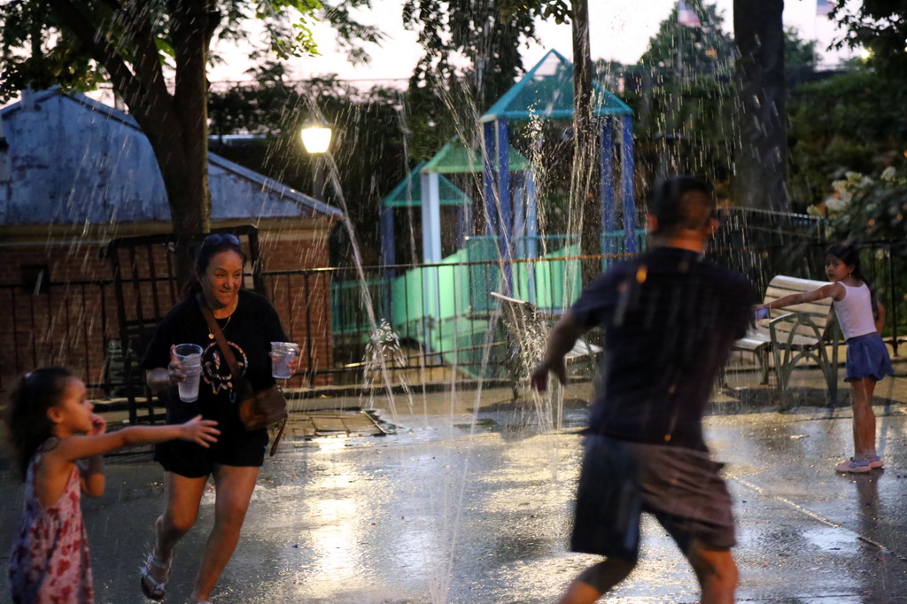 6月24日，人們在美國紐約皇后區一處噴泉戲水消暑。