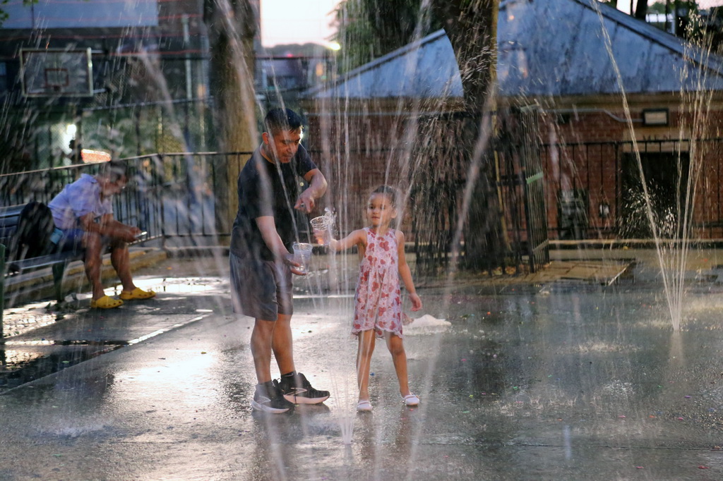 6月24日，人們在美國紐約皇后區一處噴泉戲水消暑。