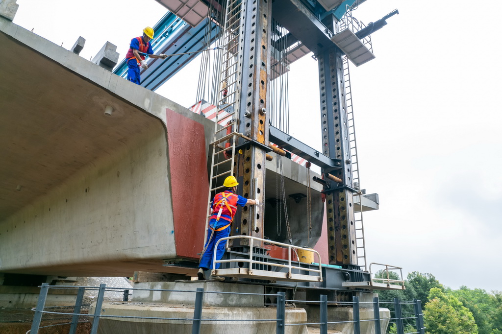 6月25日，在邵永高鐵柘刺坪特大橋建設工地，中鐵五局工人在進行架梁施工作業（無人機照片）。