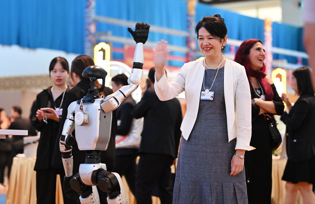 6月25日，嘉賓在第十六屆夏季達沃斯論壇文化之夜上和人形機器人互動。新華社記者 李然 攝