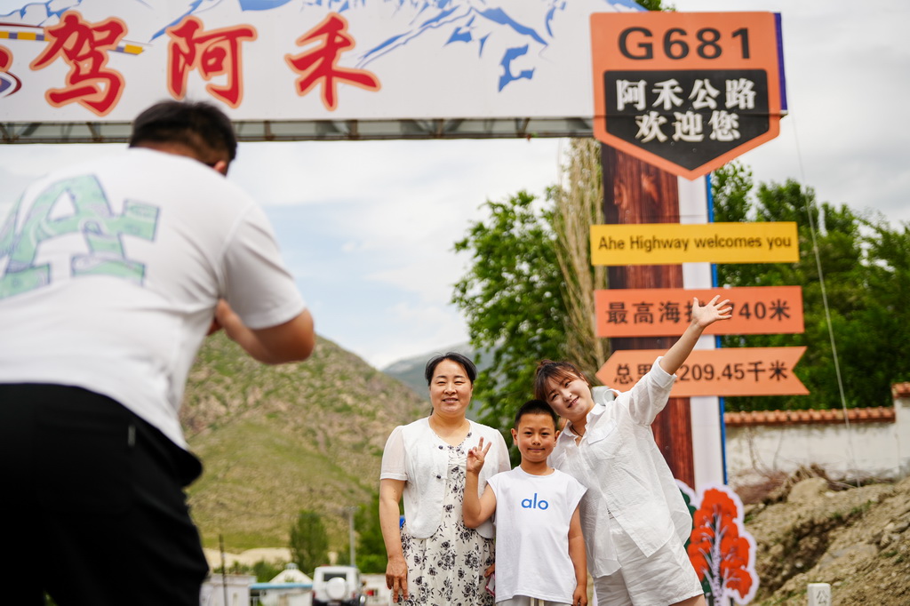 6月30日，游客在阿禾公路一處打卡點拍照留念。