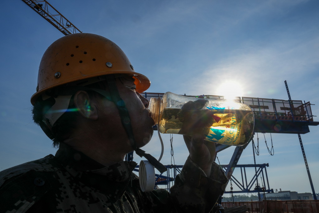 7月3日，中鐵上海工程局的工人在寧淮城際鐵路（南京至淮安）5標項目跨203縣道連續梁施工現場喝水。