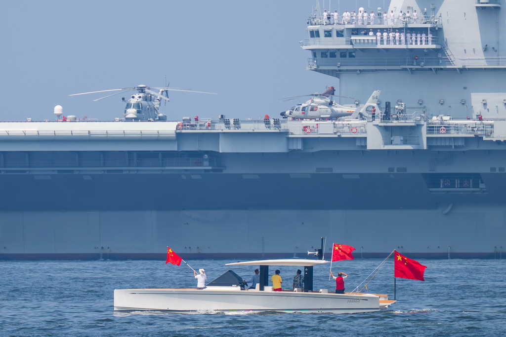 7月7日，市民乘船手舉國旗敬禮，為山東艦送行。新華社記者 朱煒 攝