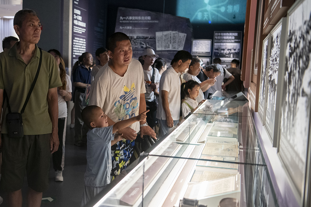 2025年7月8日，在中國人民抗日戰爭紀念館，一位家長帶著孩子參觀抗戰勝利80周年主題展。