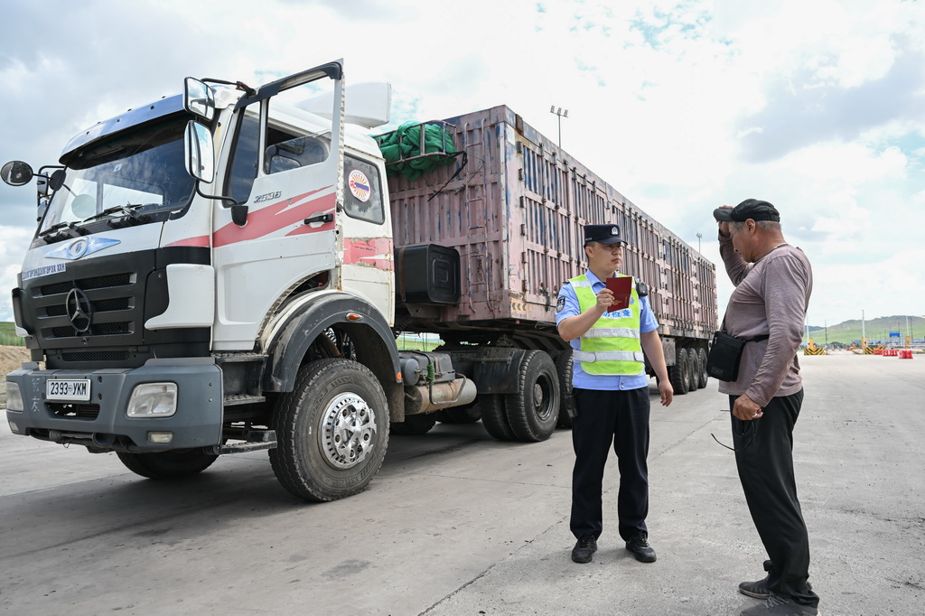 7月10日，在珠恩嘎達布其口岸，珠恩嘎達布其出入境邊防檢查站移民管理警察（左）查驗貨車司機證件。
