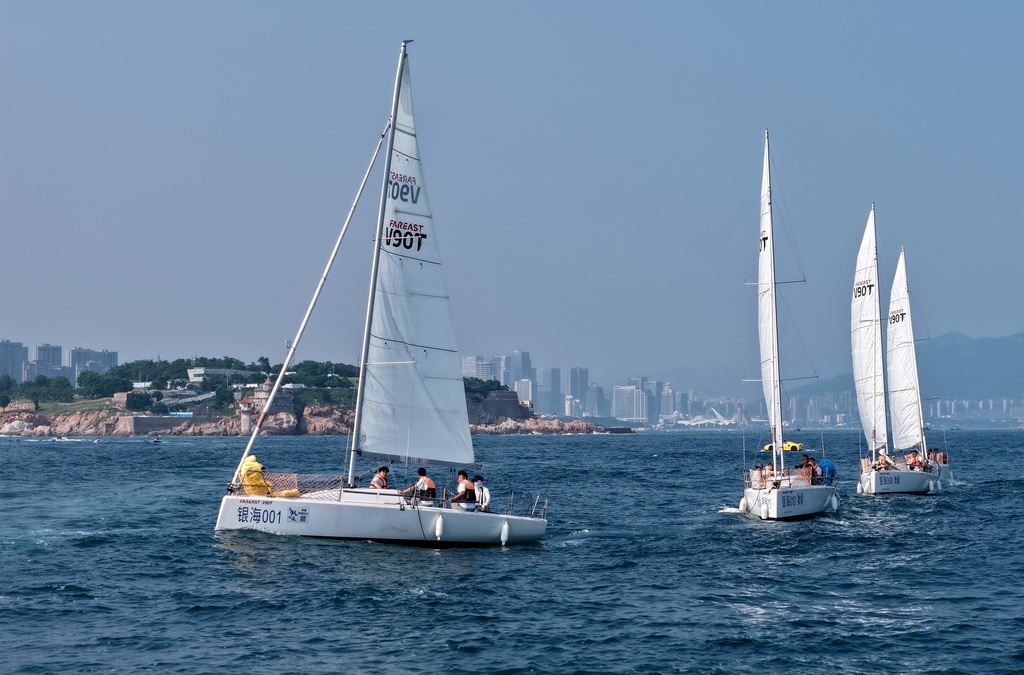 青島小麥島附近海域，市民和游客乘坐帆船參加海上巡游活動（7月10日攝，無人機照片）。