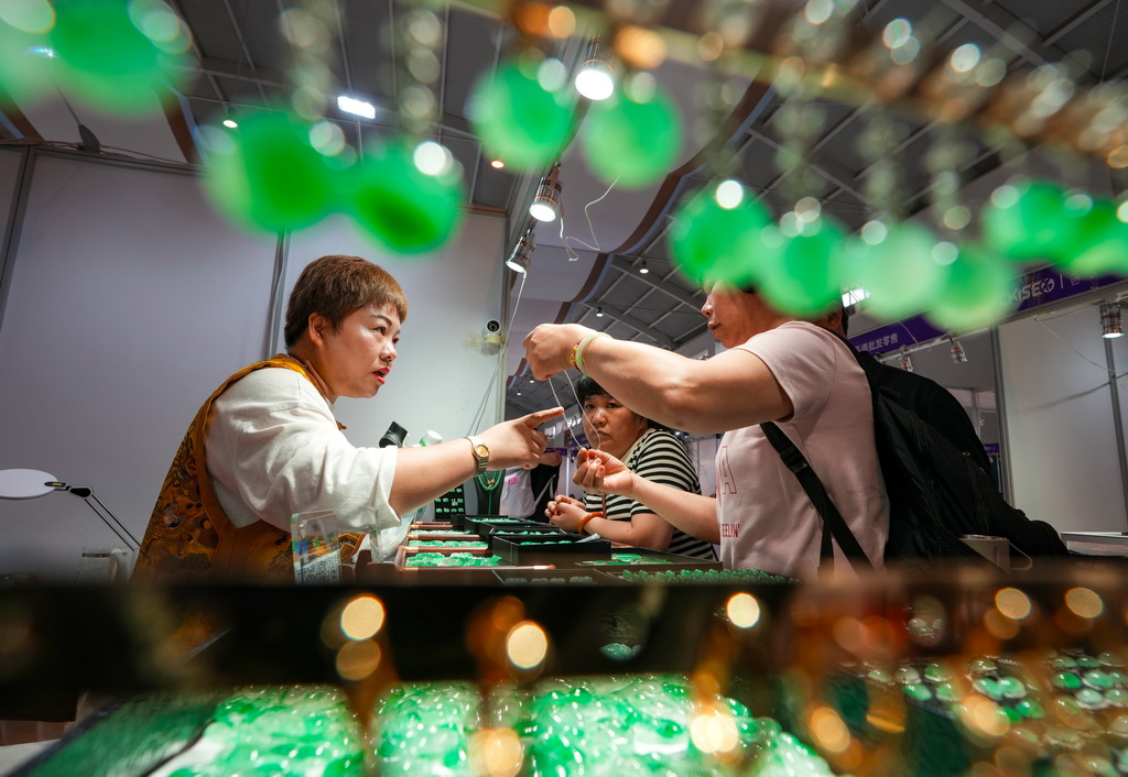 7月10日，參展商（左）在昆明石博會上向消費者介紹玉石。