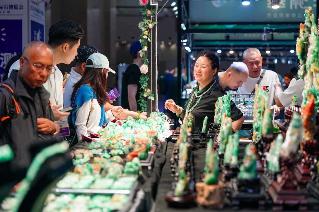 7月10日，參展商（右三）在昆明石博會上售賣玉石。