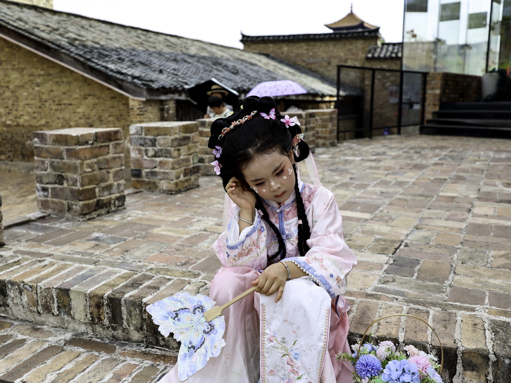 7月13日，一名小游客在江西省景德鎮市陶陽里歷史文化街區休憩。