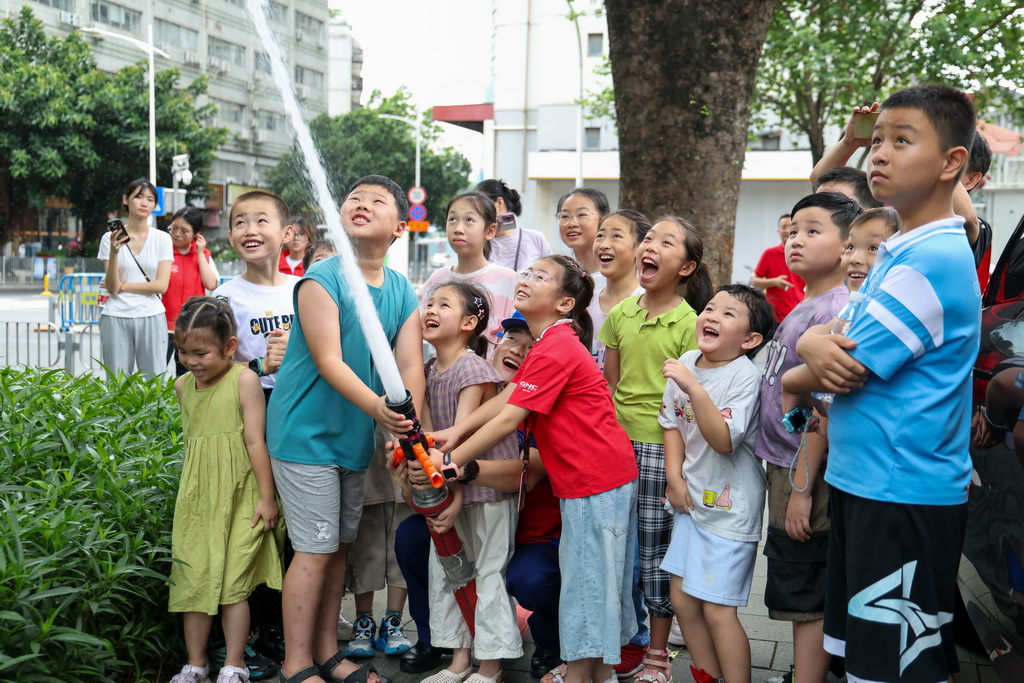 7月15日，小朋友在深圳市福田區梅豐小型消防站開放日活動中體驗多功能消防水槍。