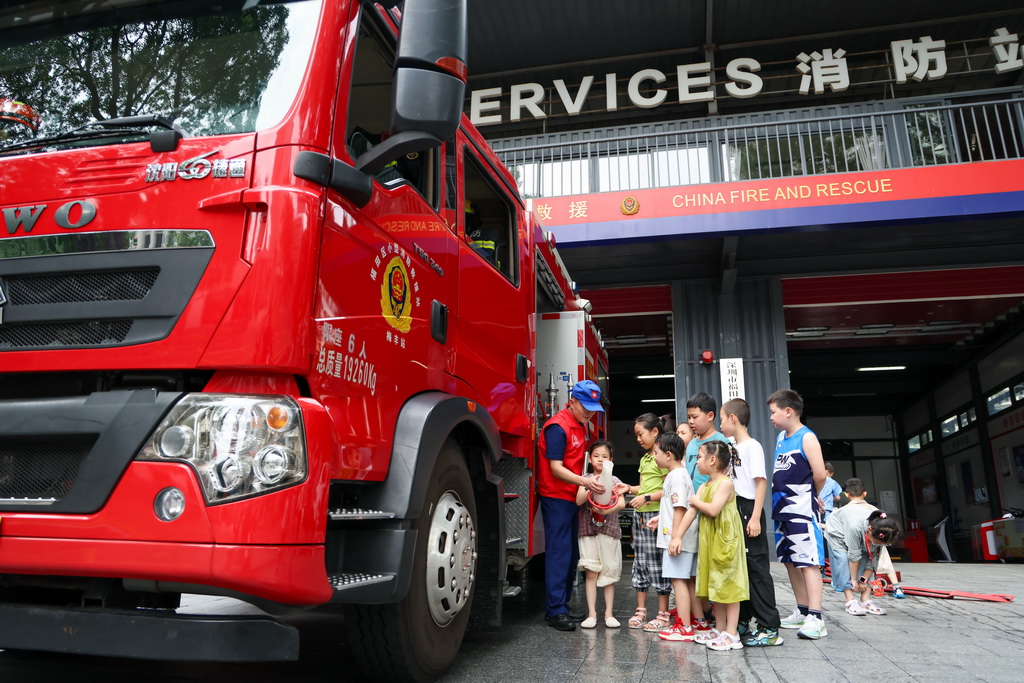 7月15日，站長孫航（左一）在深圳市福田區梅豐小型消防站開放日活動上為小朋友科普消防知識。
