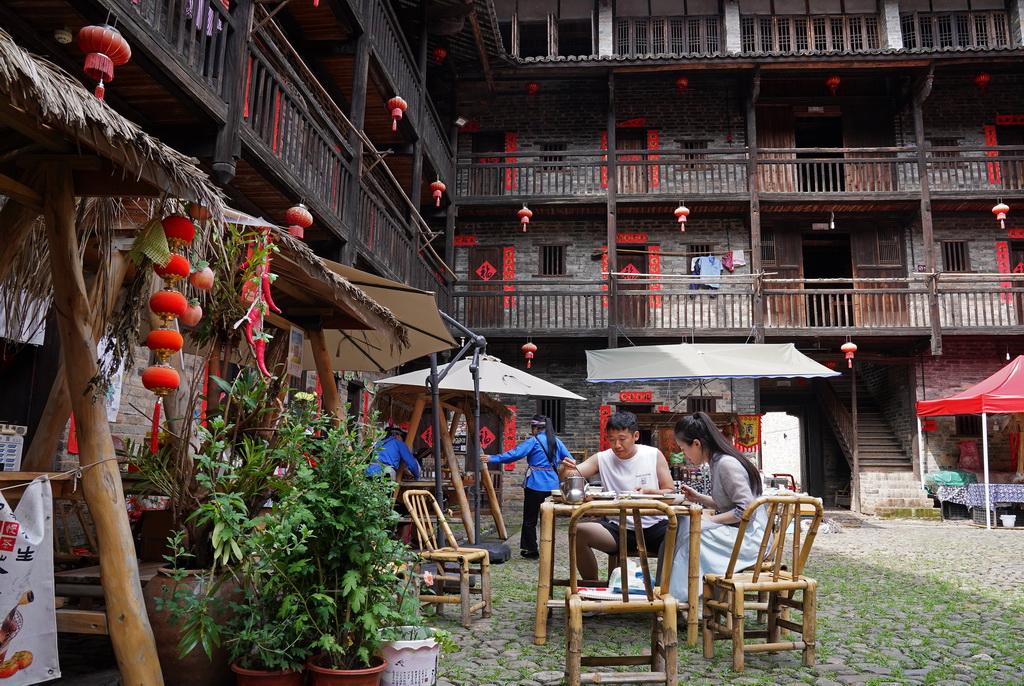 游客在龍南市楊村鎮的燕翼圍內品嘗客家土菜（6月19日攝）。