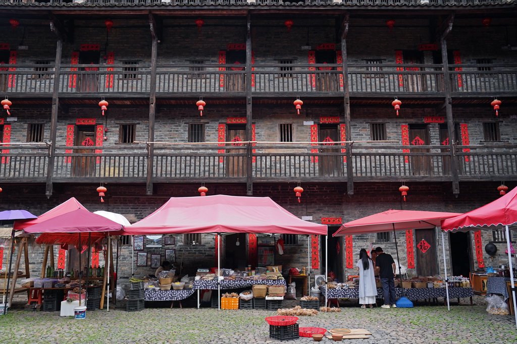 游客在龍南市楊村鎮的燕翼圍內選購村民的土特產（6月19日攝）。