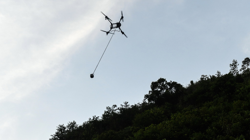 橋隧工人遙控無人機給隧道山體上的施工點運送混凝土（7月15日攝）。