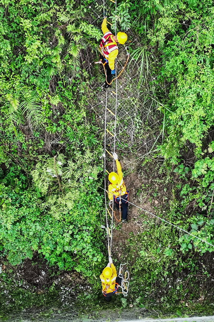 橋隧工人巡查隧道頂部的被動網（7月15日攝，無人機照片）。