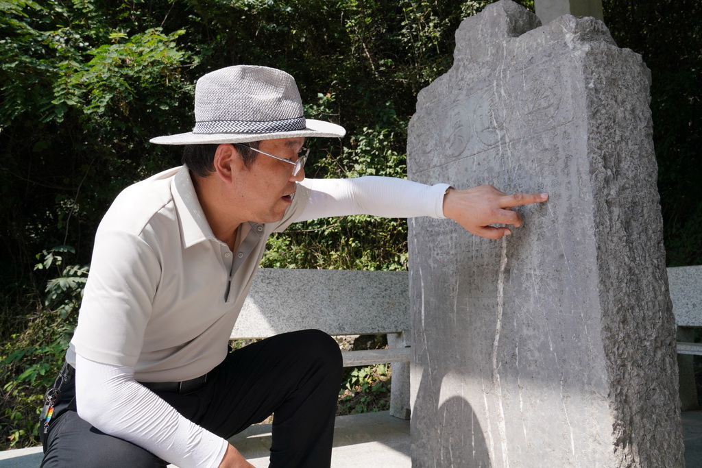 7月14日，在青泥嶺上，徽縣博物館文博副研究館員曹鵬雁在介紹一塊刻有“遠通吳楚”字樣的清代石碑。新華社記者 馬寧 攝