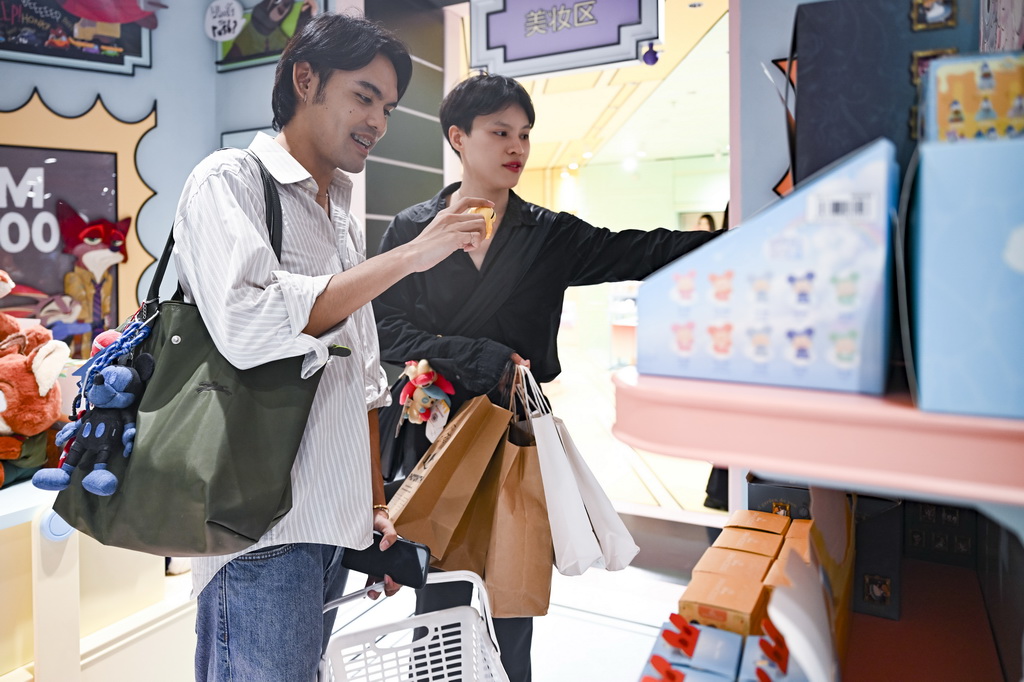 7月17日，兩名泰國游客在位于上海市南京路步行街的一家潮玩店里挑選商品。新華社記者 陳浩明 攝
