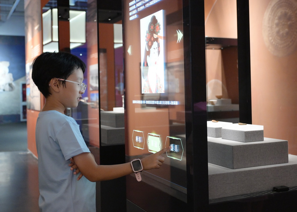 7月28日，一名小朋友在展廳內體驗文物智能展柜。