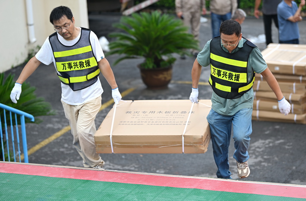 7月28日，救援人員在天津市薊州區下營鎮初級中學安置點搬運床鋪。