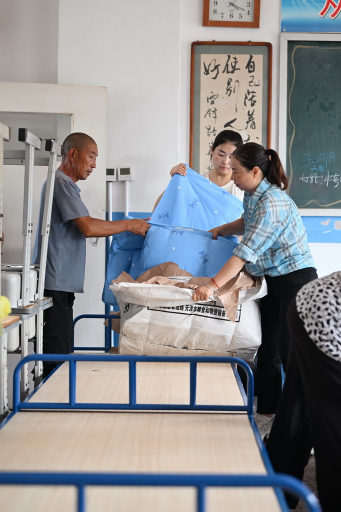 7月28日，人們在天津市薊州區下營鎮初級中學安置點鋪設被褥。