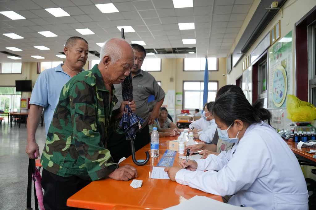 7月29日，在北京市密云區太師莊中學居民安置點，太師屯鎮社區衛生服務中心的醫生（右）為安置在此的群眾開藥。