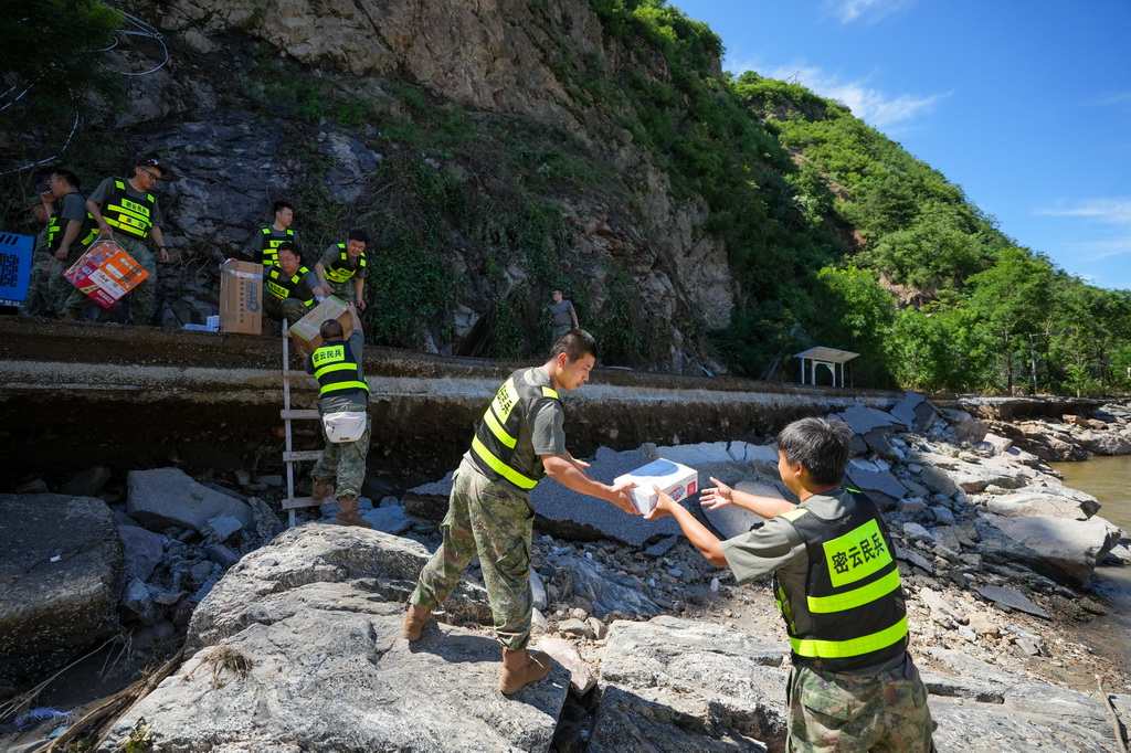 7月30日，在密云區馮家峪鎮三岔口村，救援人員為村民運送生活物資。