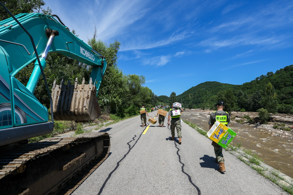 7月30日，在密云區馮家峪鎮，救援人員為道路被阻斷的村莊運送生活物資。