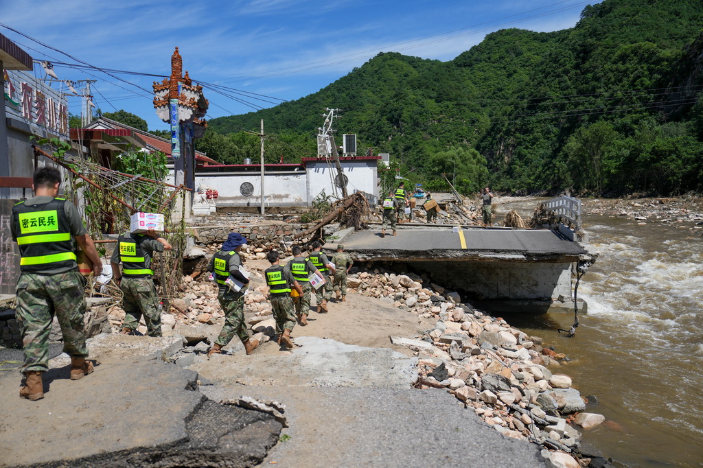 7月30日，在密云區馮家峪鎮，救援人員為道路被阻斷的村莊運送物資。