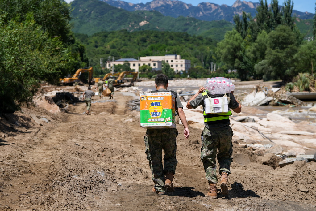 7月30日，在密云區馮家峪鎮，救援人員為道路被阻斷的村莊運送生活物資。