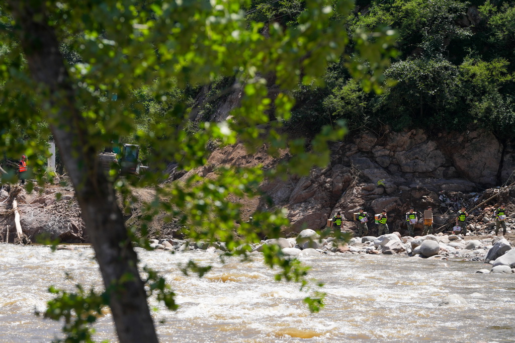 7月30日，在密云區馮家峪鎮，救援人員為道路被阻斷的村莊運送物資。