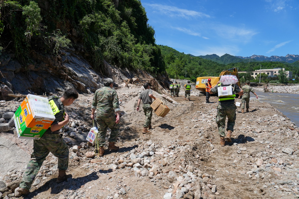 7月30日，在密云區馮家峪鎮，救援人員為道路被阻斷的村莊運送生活物資。