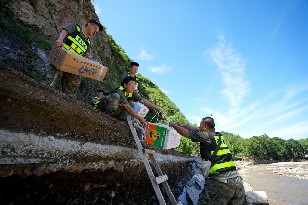 7月30日，在密云區馮家峪鎮三岔口村，救援人員為村民運送物資。