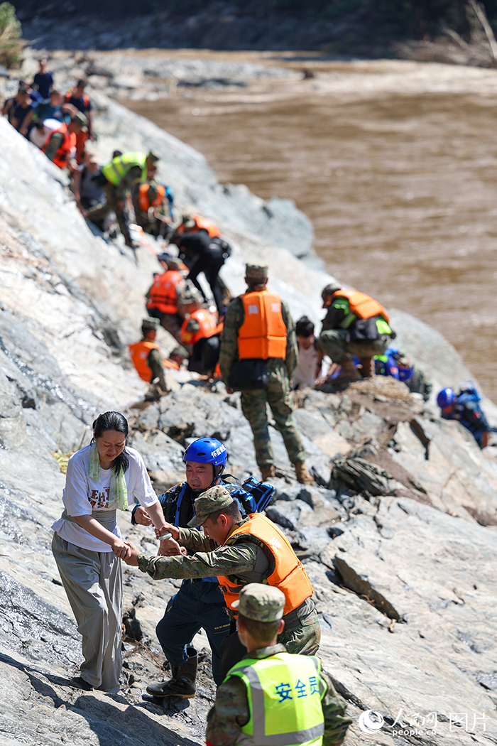 7月29日，北京市懷柔區琉璃廟鎮雙文鋪村附近，解放軍陸軍某部官兵和藍天救援隊隊員協助受困游客和村民們轉移。