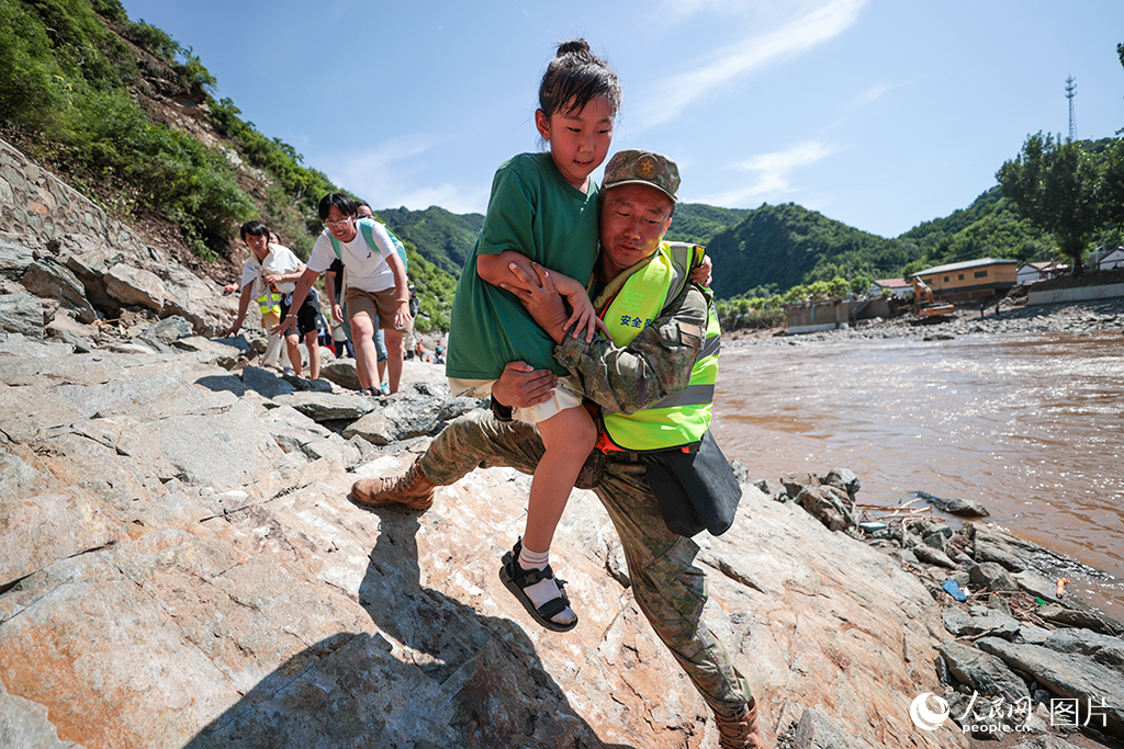 7月29日，北京市懷柔區琉璃廟鎮雙文鋪村附近，解放軍陸軍某部官兵協助受困游客和村民們轉移。