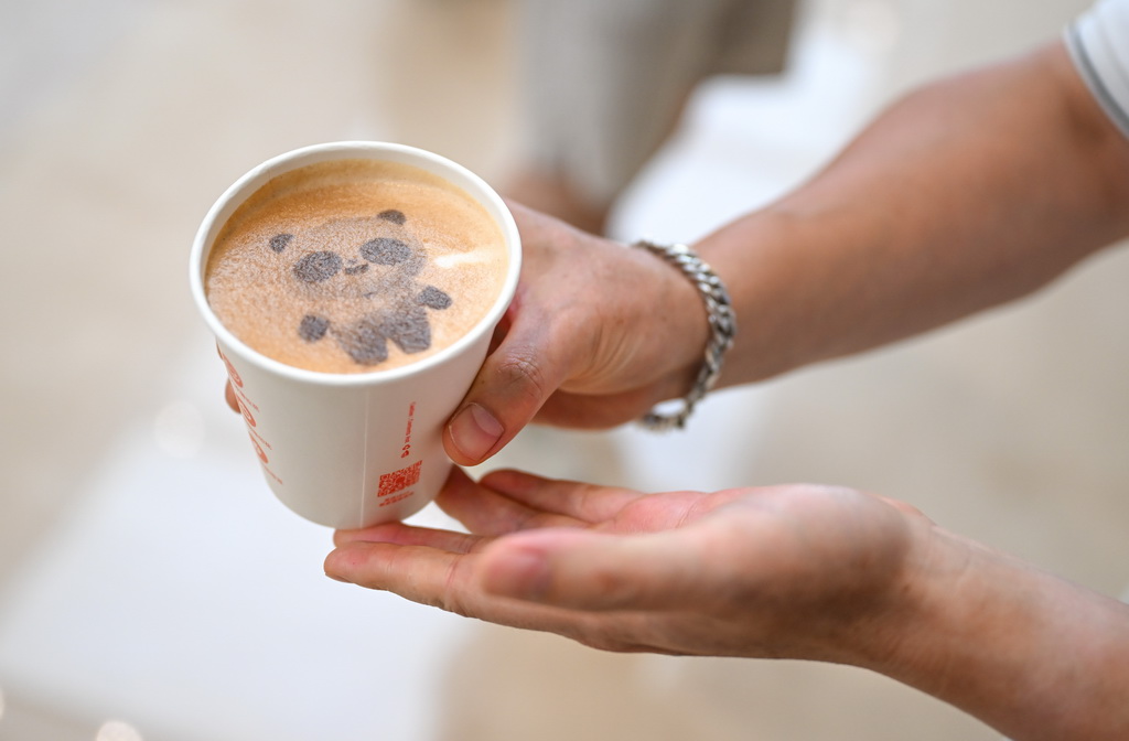 8月4日，一名媒體記者在成都世運會主媒體中心展示由咖啡機器人制作的帶有吉祥物“蜀寶”圖案的飲品。新華社記者 貝赫 攝