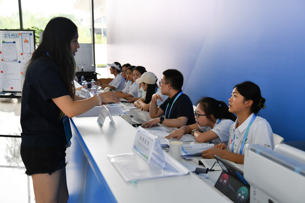 8月4日，志愿者（右一）在成都世運會主媒體中心提供信息咨詢服務。新華社記者 張博文 攝