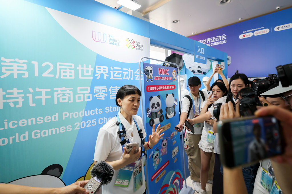 8月4日，工作人員（左一）在成都世運會主媒體中心為媒體記者介紹特許商品。新華社記者 王翔 攝