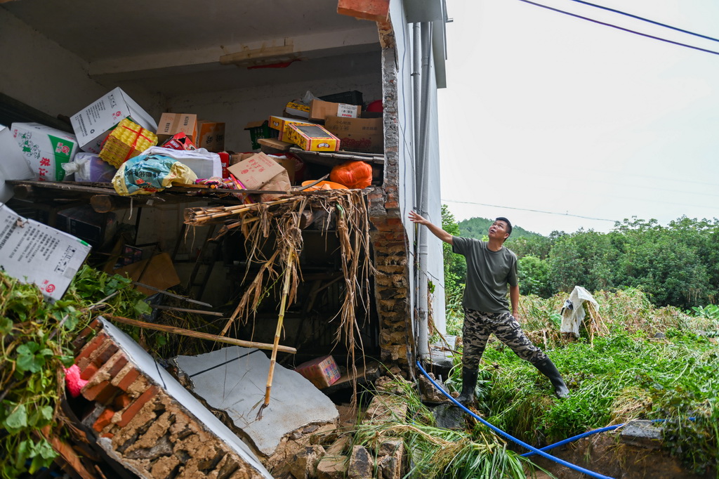 8月6日，廣東清遠佛岡縣石角鎮黃花村黨委書記李庚原在一棟被沖毀的房屋旁了解房屋受損情況。
