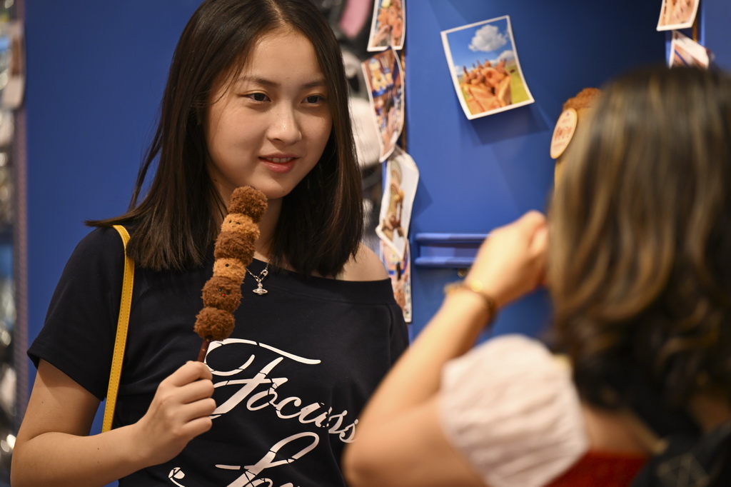 8月21日，在烏魯木齊大巴扎步行街，游客手持文創產品拍照留影。