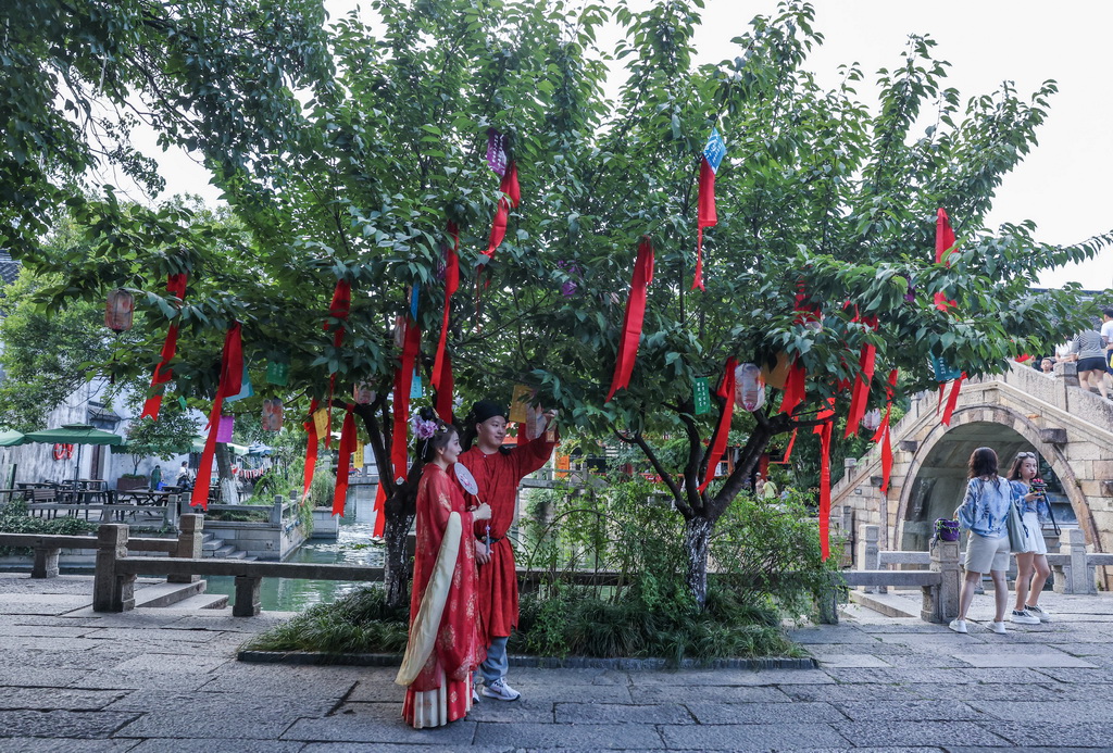 8月26日，在嘉興市南湖區月河歷史街區，游客身著傳統服飾在七夕許愿樹下拍照。