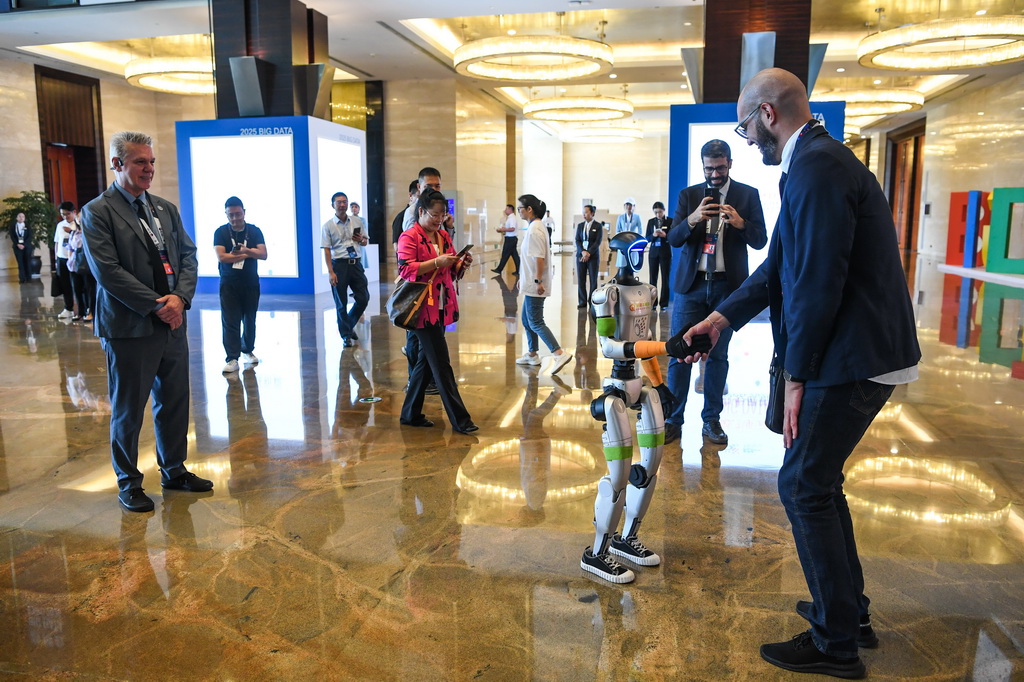 8月28日，參會人員在2025中國國際大數據產業博覽會開幕式現場與一款機器人互動。