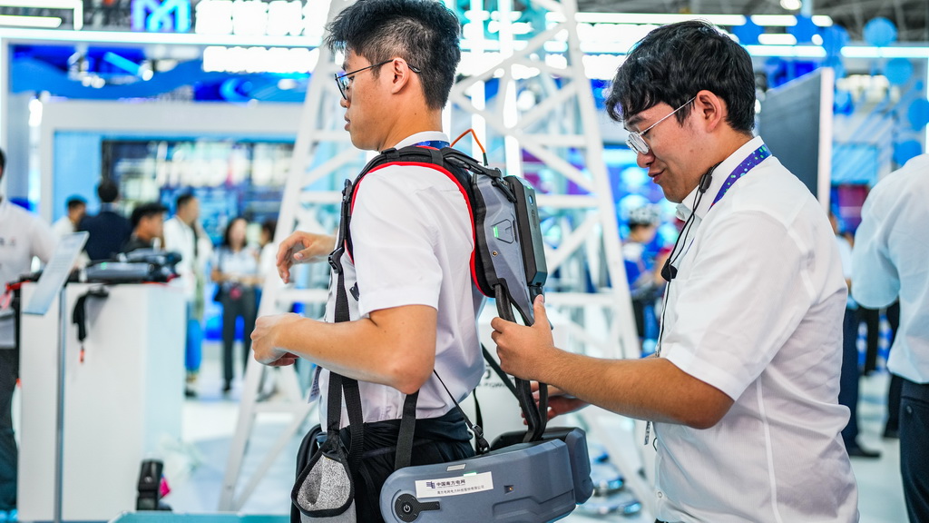8月28日，南方電網工作人員在數博會上幫觀展者佩戴攀登用外骨骼。新華社記者 陶亮 攝