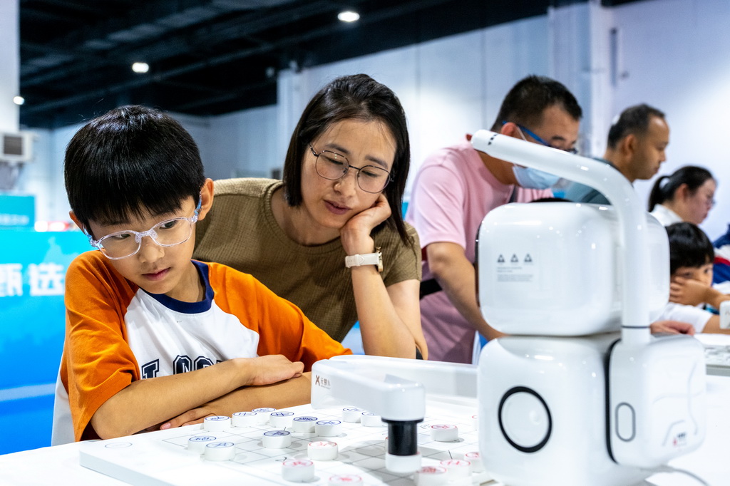 8月31日，在內蒙古呼和浩特市2025北疆書展，小朋友與AI下棋機器人對弈。