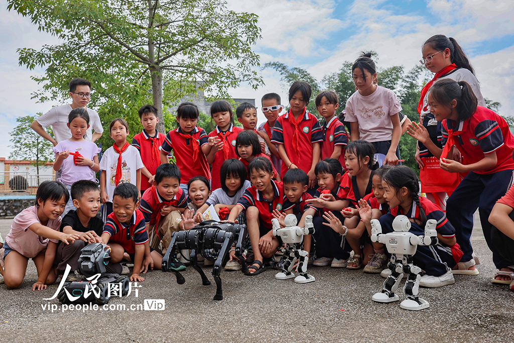 2025年9月11日，在廣西賀州市八步區靈峰鎮中心學校，學生與機器人、機器狗互動。學校通過科普知識講解激發學生創新創造意識和科學探索精神，讓師生在互動與體驗中感受科技的魅力。黎豪圖攝（人民圖片網）