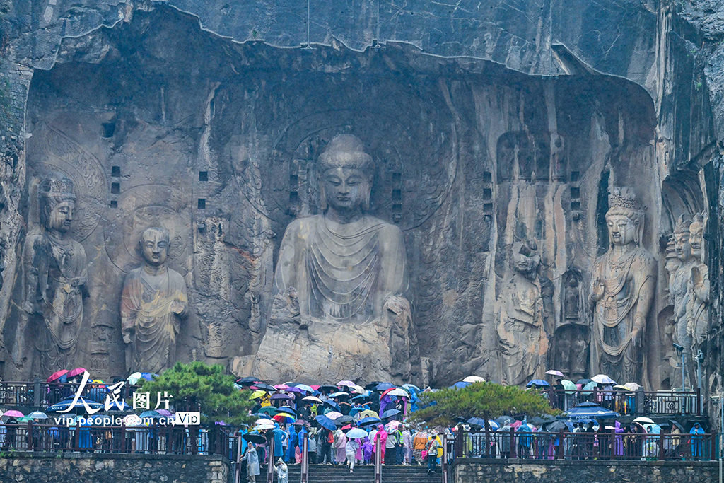 10月1日是國慶假期第一天，游客冒雨游覽河南洛陽的龍門石窟。李衛超攝（人民圖片網）