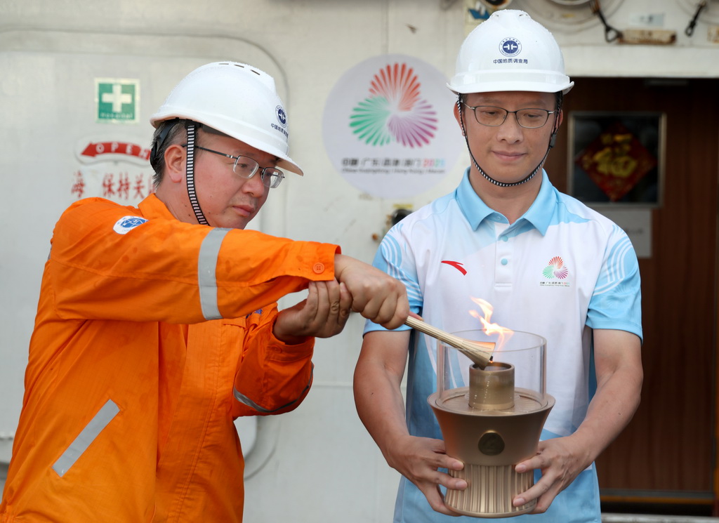 在科考船甲板面，“源火”采集組副組長，廣州海洋地質調查局副總工程師沙志彬（左）用引火棒將“源火”轉移至“源火”盒（9月18日攝）。