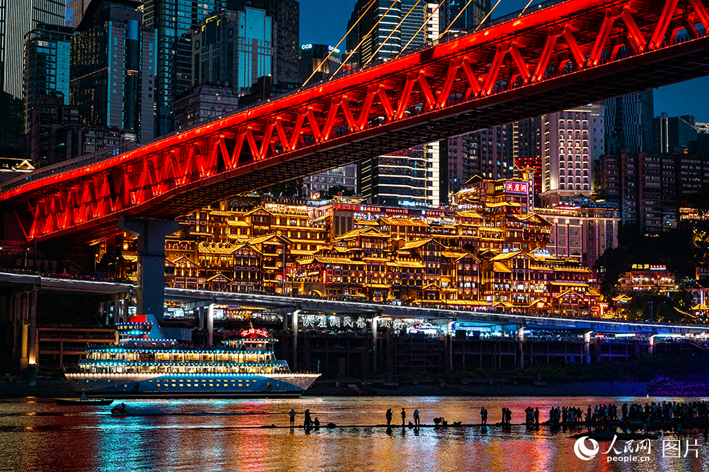 長江經濟帶重要節點城市重慶，嘉陵江與長江交匯處左岸，地標性景觀洪崖洞以巴渝傳統吊腳樓為形、現代光影技術為魂，層層疊疊的樓閣被暖黃燈光勾勒出立體輪廓，倒映碧波形成“千與千尋”般的魔幻鏡像。夜色中，游客在江邊漫步，歡笑聲與江輪鳴笛聲交織——這一融合歷史文脈與現代活力的“長江夜經濟明珠”，既是長江上游生態人文協同發展的生動縮影，更以文旅融合新場景展現著長江經濟帶綠色轉型中的城市創新實踐。人民網記者 鄒樂攝