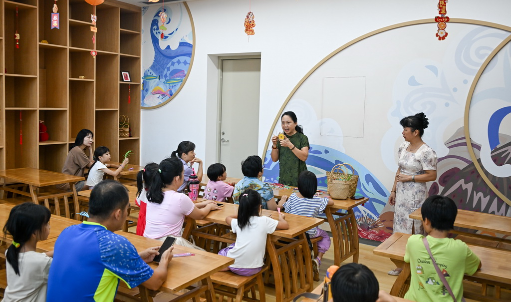 10月12日，在海南省文化館，東山草編技藝傳承人袁潔（后中）為家長和小朋友們講解東山草編技藝。