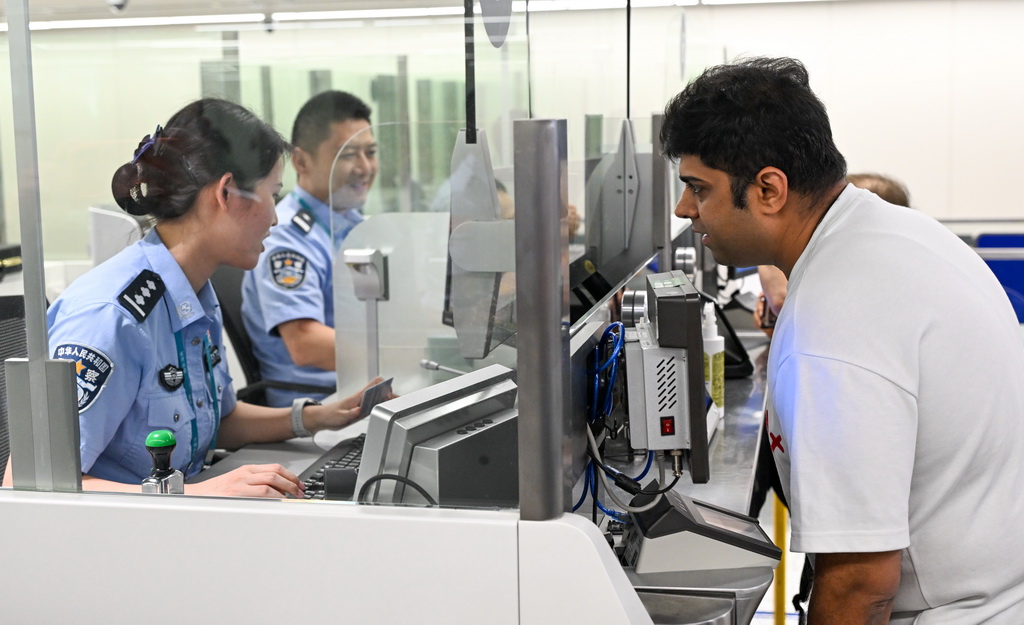10月15日，在?？诿捞m邊檢站，海南2025年第200萬名通關外籍旅客卡迪克（右）在辦理邊檢手續。