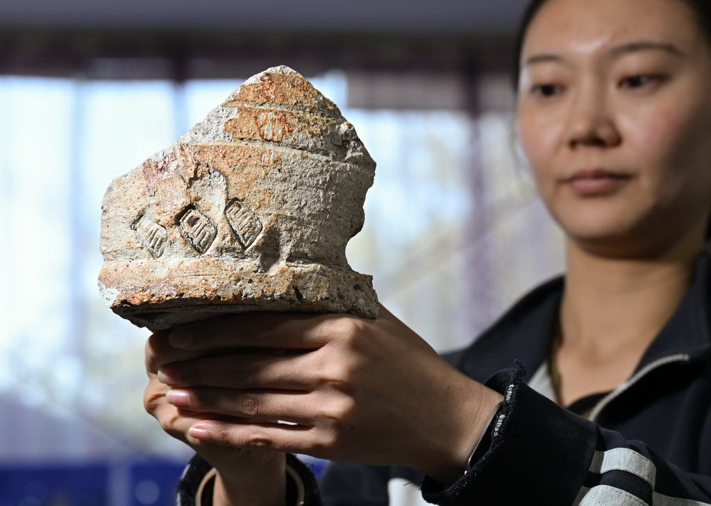 一位工作人員在蘇峪口瓷窯址考古隊文物庫房內展示遺址出土的帶有“官”字款的匣缽殘片（10月13日攝）。新華社記者 李賀 攝